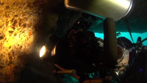 hombre de cámara submarina filmando de cerca en una cueva con carcasa submarina y luz de vídeo