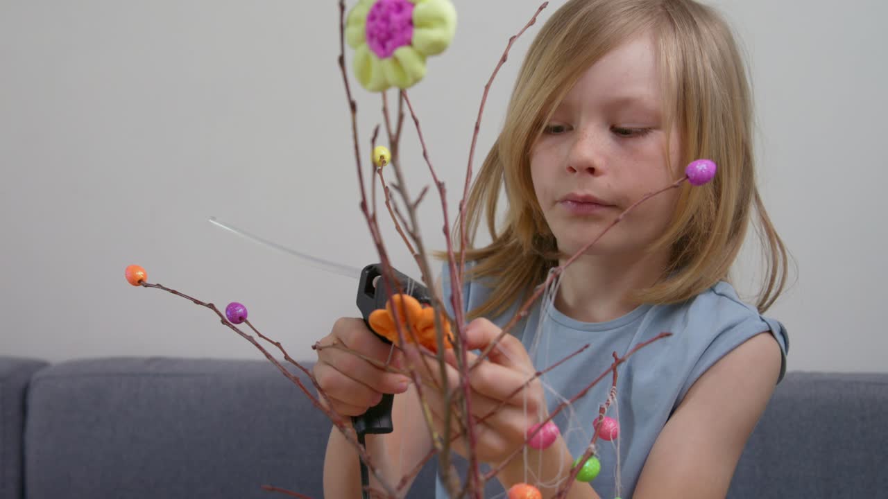 Young Girl Decorating Easter Branches with a Glue Gun