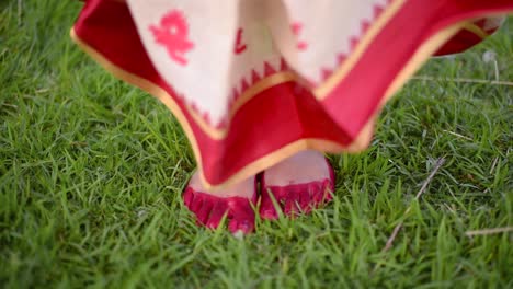 feet of a newly wed married indian woman comes and stops on grass, feet with alta or red dye