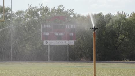 sprinkler head spraying water on a texas high school football field friday night lights