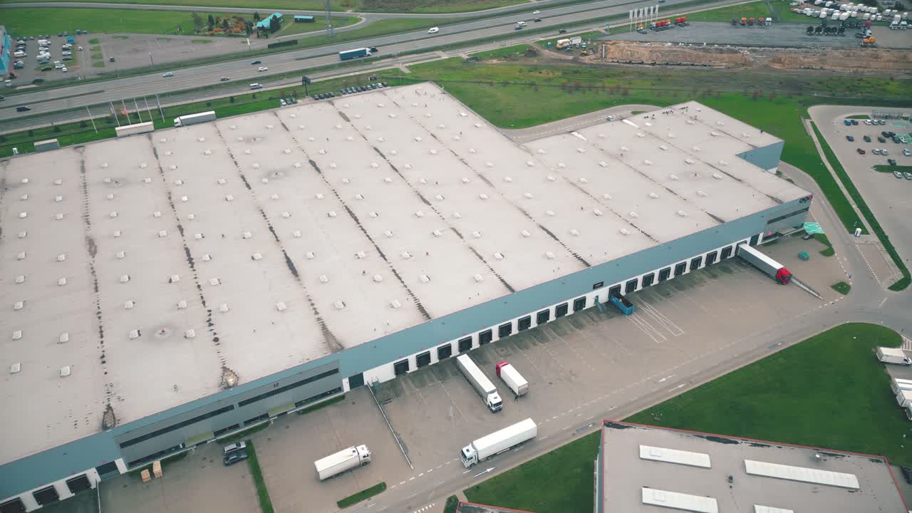 Edifici di un centro logistico, magazzini vicino all'autostrada, vista dall'alto, un gran numero di camion nel parcheggio vicino al magazzino.