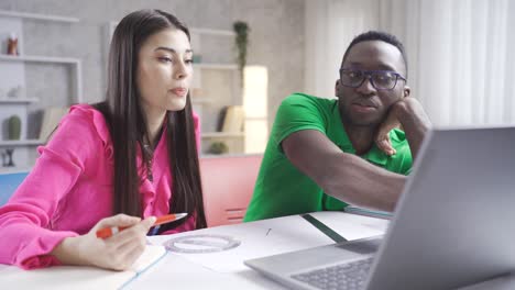 portrait of freelance young man and woman. young african man and caucasian woman working with laptop.