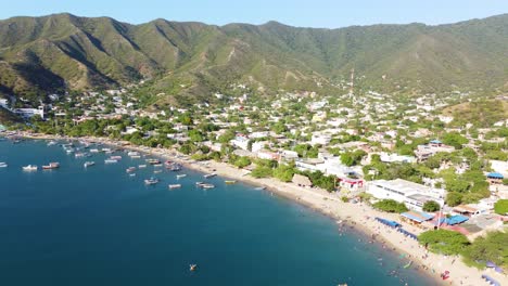 Toma-Aérea-De-Un-Dron-Acercándose-A-La-Playa-Y-La-Ciudad-De-Santa-Marta-Pasando-Sobre-Las-Hermosas-Aguas-Azules-Del-Mar-Caribe-En-Magdalena,-Colombia,