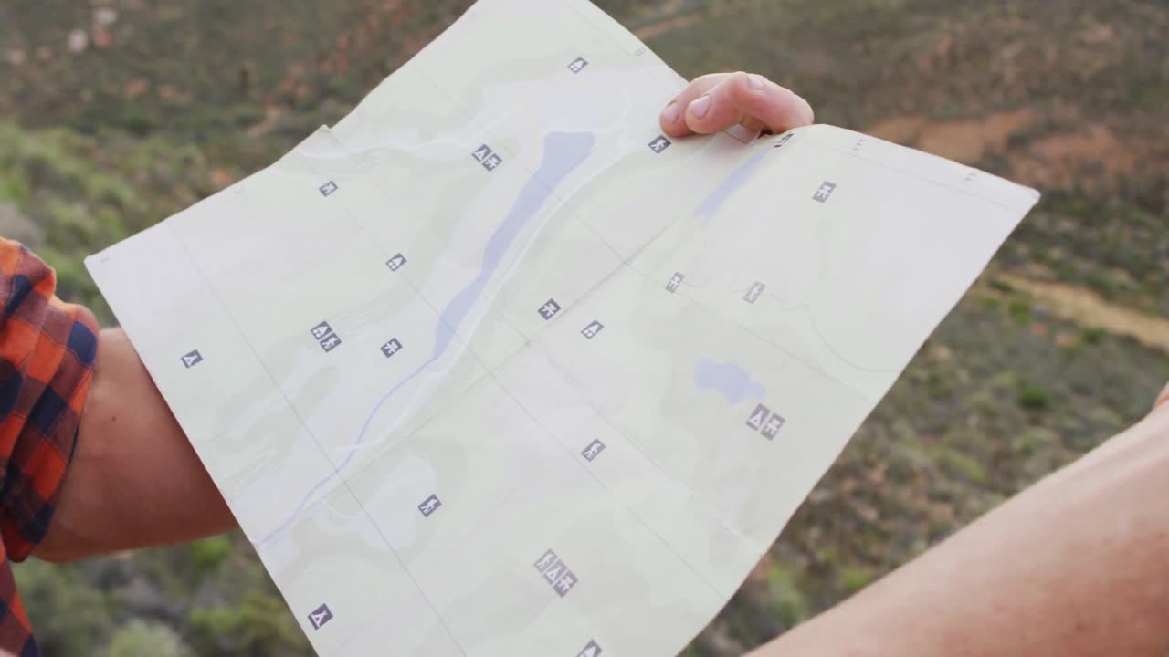 야생 의 산 꼭대기 에 앉아 지도를 들고 있는 백인 남성 생존자