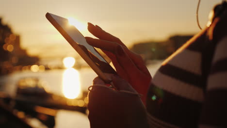 hands of a woman with a smartphone on the background of a pier with yachts at sunset 4k video