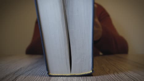 Woman-closes-book-on-a-wooden-table---Slow-Motion