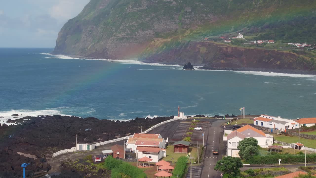 Vista aérea da vila de Fajã Grande na costa acidentada da Ilha das Flores, com casas e fortes ondas do Atlântico Norte.