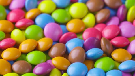 slow motion close-up of round colorful chocolate candies, dragee. rotation and fall multicolored chocolate candies