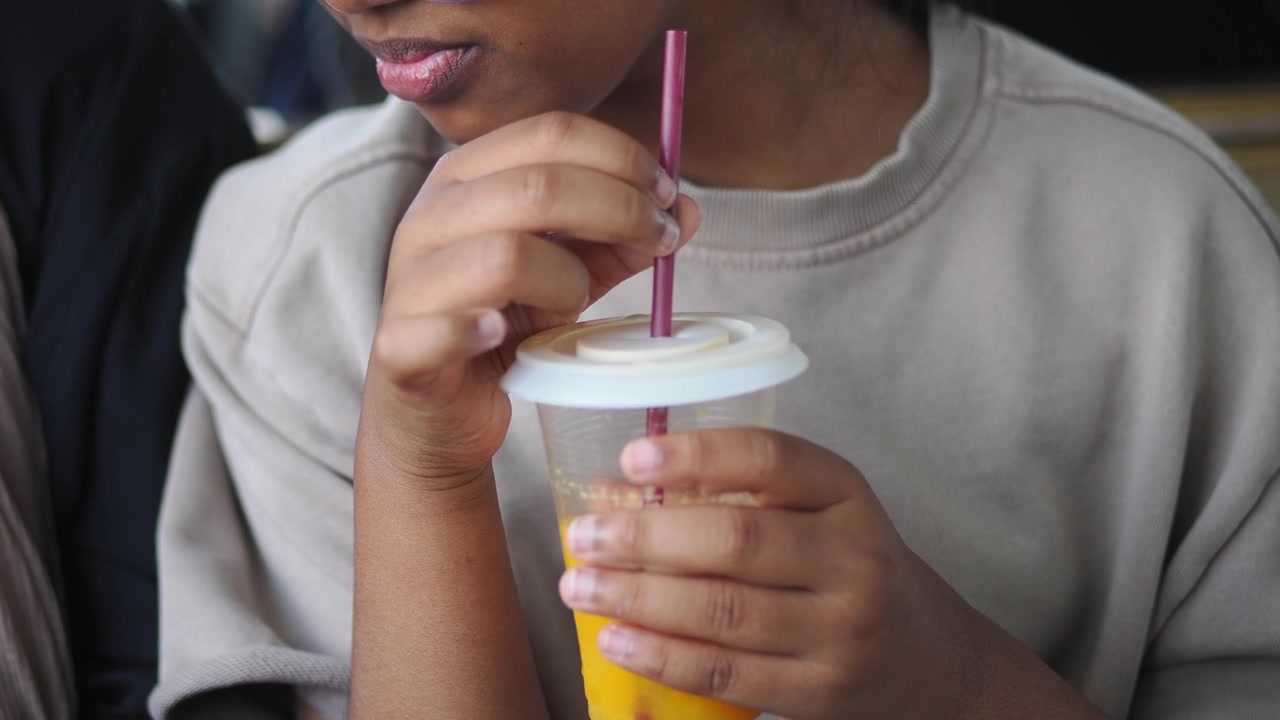 Giovane che beve succo d'arancia da un bicchiere di plastica