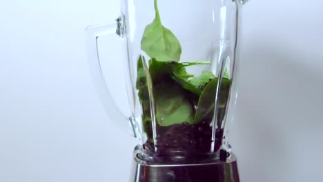 espinacas cayendo en la licuadora, sobre arándanos, batido saludable