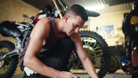 Close-up-shot:-a-man-with-short-hair-in-a-gray-T-shirt-selects-the-necessary-tools-to-begin-repairing-the-bike