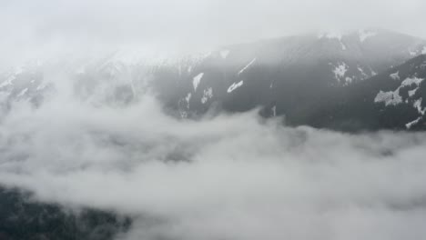 ver volar a través de las nubes hacia las montañas cubiertas de nieve