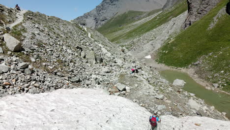 Aerial-view-of-a-man-walking-through-a-marked-path-in-the-snow-in-Zinal-valley,-Switzerland