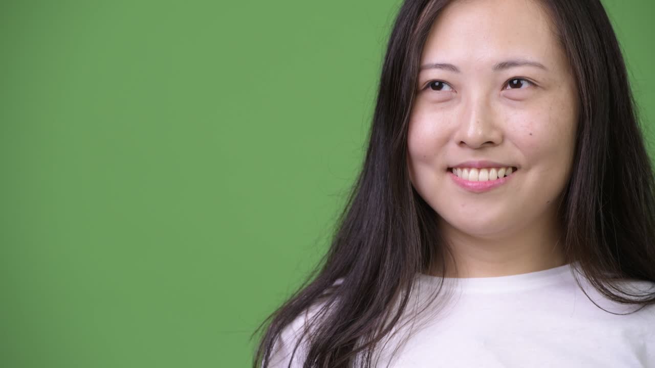 Young happy Asian woman thinking