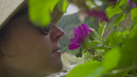 Woman-smells-wild-flower-during-hike-along-trail-in-Oregon