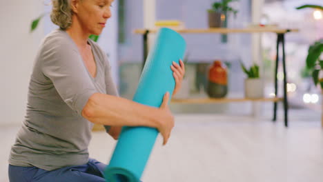 Mature-woman-rolling-a-yoga-mat-after-calming