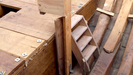 panning shot right to left of early stages of wooden boat construction