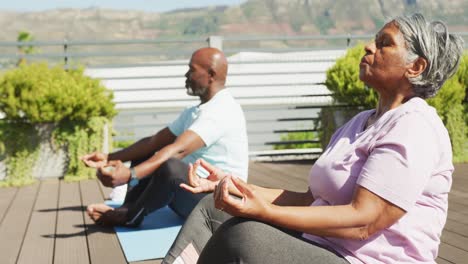 Video-of-relaxing-senior-african-american-couple-meditating-in-the-garden