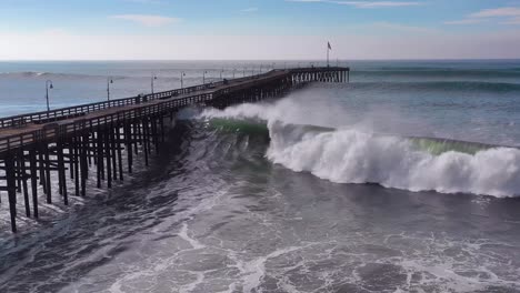 aerial over huge waves rolling in over a california pier in ventura california during a big winter storm suggests global warming and sea level rise or tsunami 6