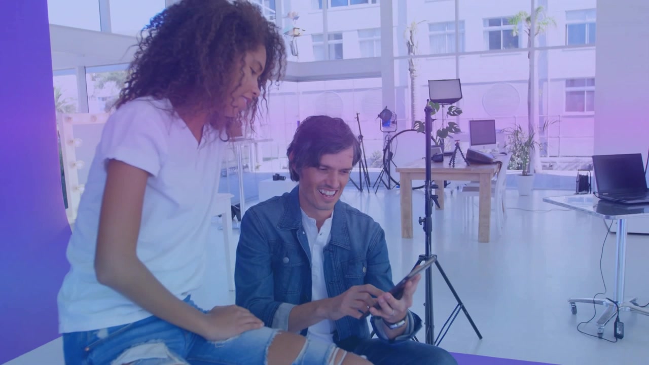 Donna che esamina i design su un tablet mentre un uomo tocca lo schermo, creando scie luminose in uno studio di design.