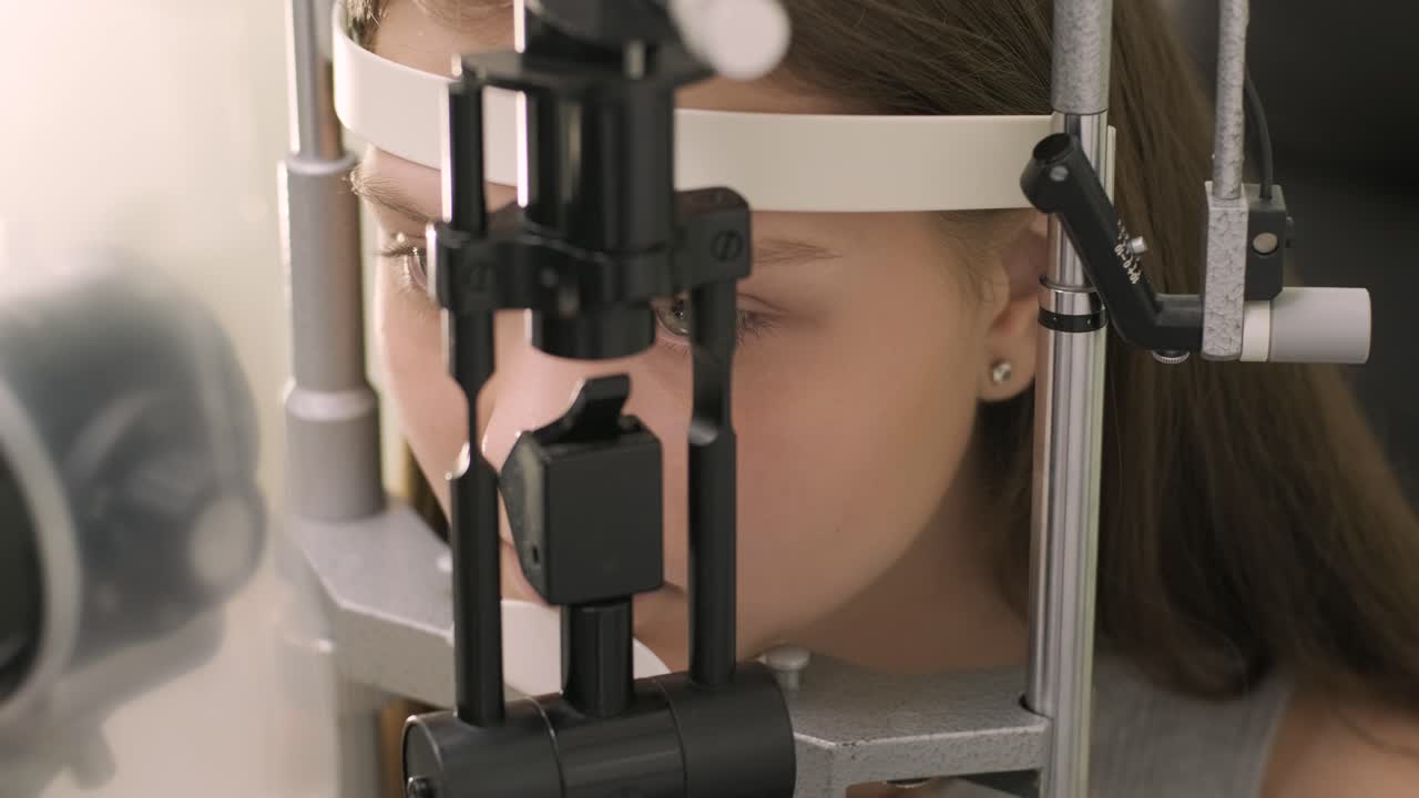 oftalmologo controlla la vista di un giovane adolescente con attrezzature moderne. medico che controlla gli occhi con un dispositivo biomicroscopico. dolly shot di una dottoressa che esamina la struttura dell'occhio con l'aiuto di attrezzature mediche