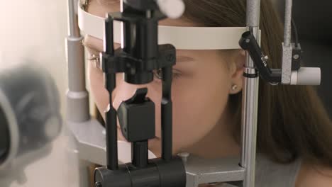 ophthalmologist check eyesight of young teen with modern equipment. doctor checking eyes with biomicroscope device. dolly shot of female doctor examining eye structure with help of medical equipment