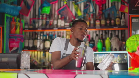barman takes shaker dropping glass in bar. young bartender performs tricks with equipment unsuccessfully. african american man prepares drinks