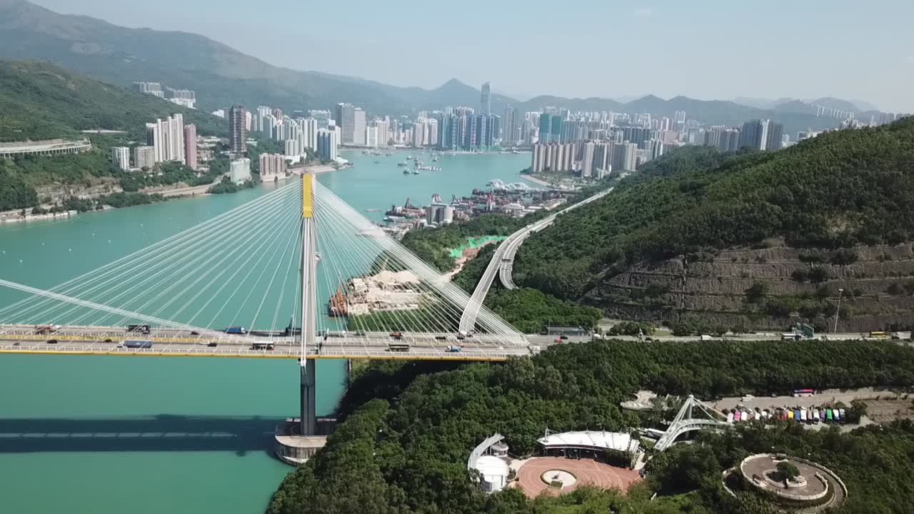 toma aérea, pista en el puente ting kau, ángulos de visión giratorios mirando a través del puente y los edificios y la montaña al fondo.