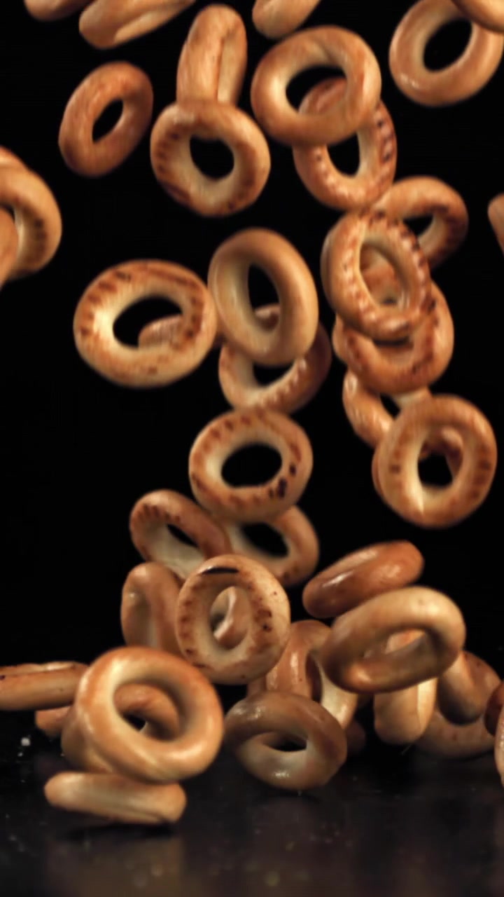 Bagel dorati che cadono al rallentatore su uno sfondo nero