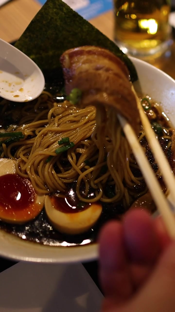 Persona che mangia ramen con le bacchette a un tavolo