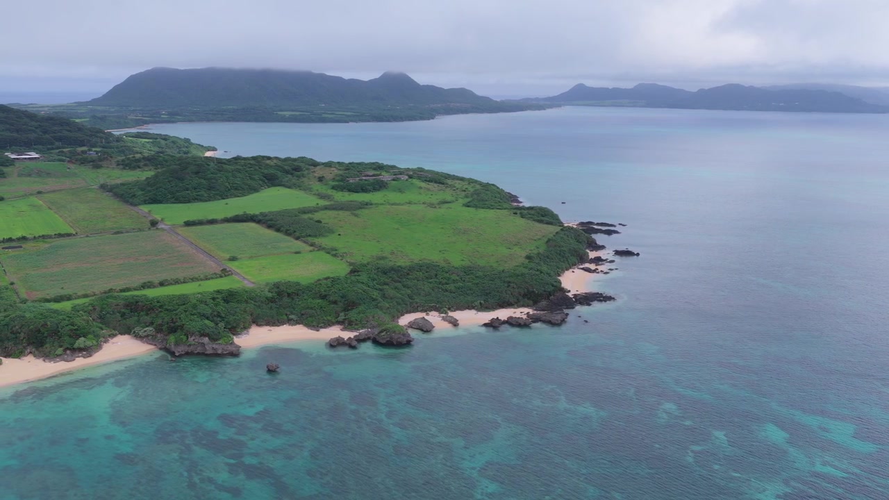 Carrellata orizzontale a sinistra lungo la costa frastagliata, i campi agricoli, le spiagge sabbiose e le acque turchesi di Nosokoniaru Beach, Isola di Ishigaki, Okinawa, Giappone.