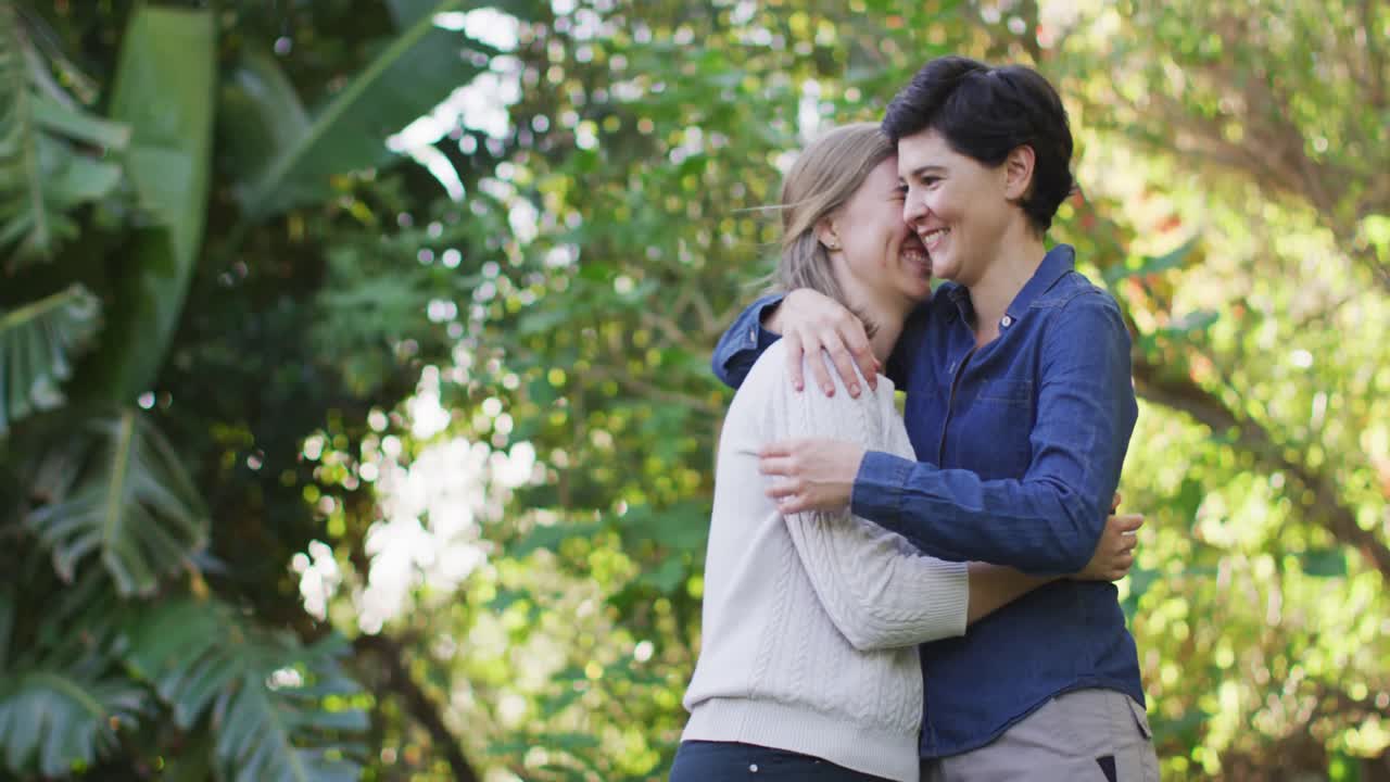 pareja lesbiana caucásica abrazándose y abrazándose en el jardín