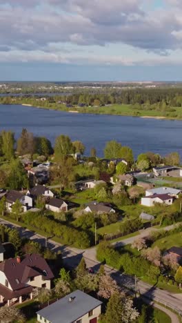 arial view of peaceful homes by a lake with green surroundings. vertical shot