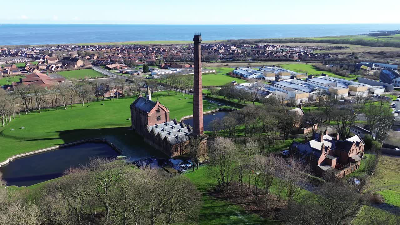 Luftaufnahme einer historischen Pumpstation mit hohem Schornstein am Meer.
