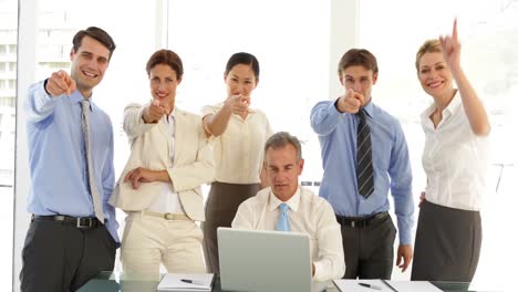 equipo de negocios frente a la computadora portátil y luego apuntando a la cámara