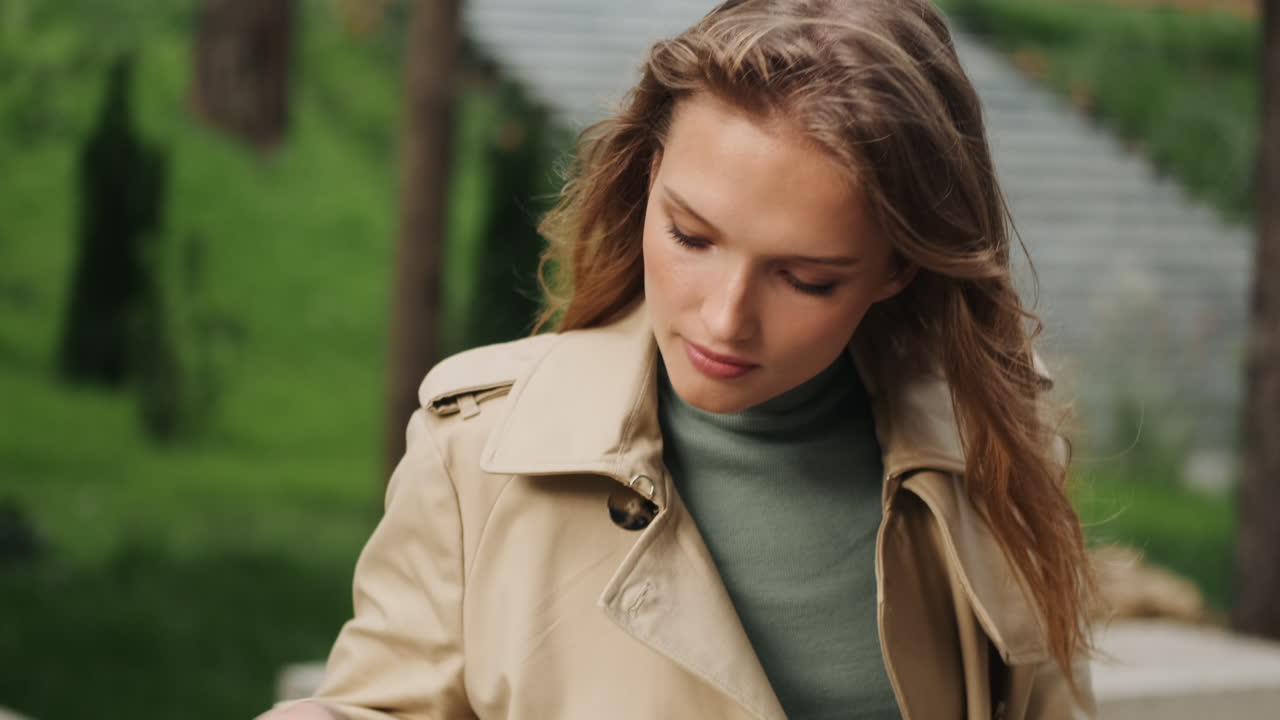 야외에서 전화로 얘기하는 백인 여성 학생.