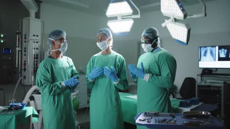retrato de cirujanos serios y diversos con guantes médicos hablando en la sala de operaciones en cámara lenta.