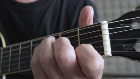 senior man sitting and playing the acoustic guitar at home