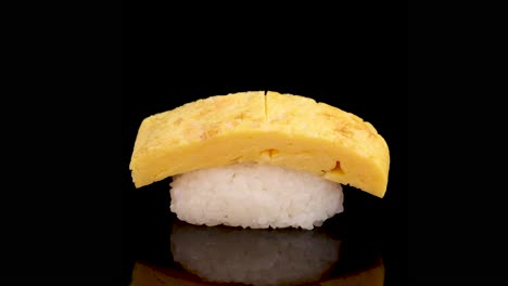 tamago egg sushi rotates smoothly on a glossy black surface, illuminated by soft studio lighting, highlighting texture and detail in a seamless motion
