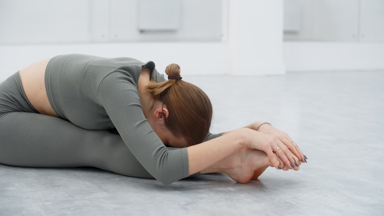 Woman practicing seated forward bend yoga pose