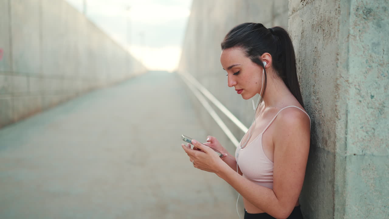 Woman using mobile phone with earphones in tunnel