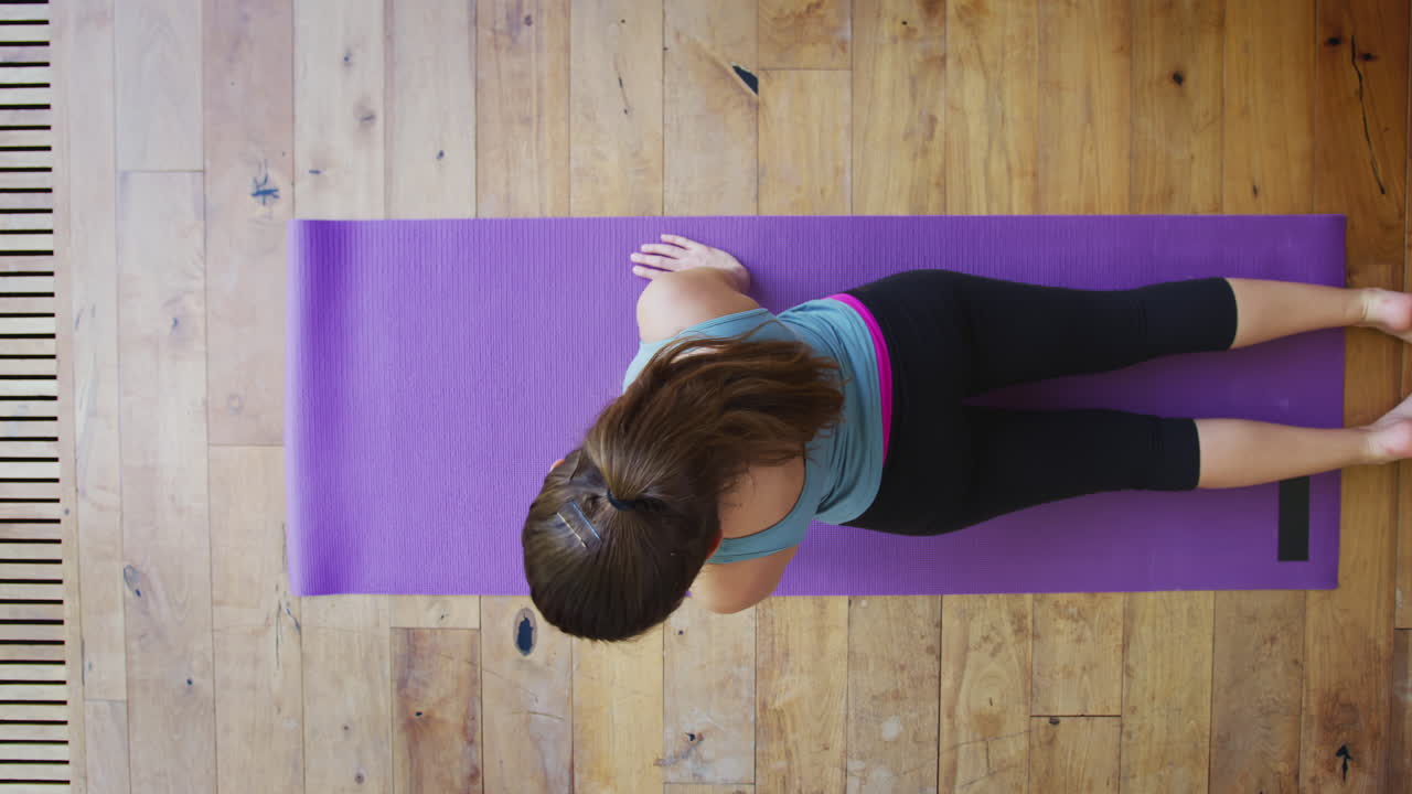 vista aérea de una mujer joven haciendo yoga en el suelo de madera