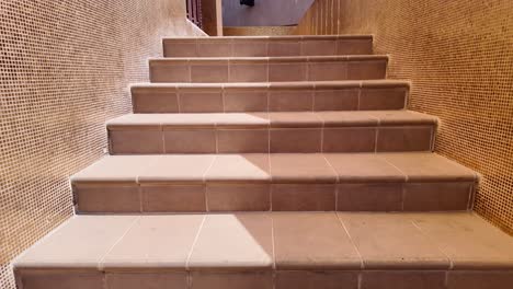 escaleras interiores de azulejos marrones con pared de mosaico dorado
