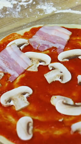 preparing a bacon and mushroom pizza