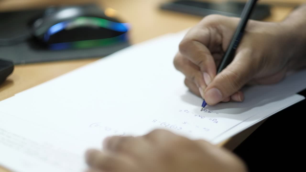 Person writing mathematical equations on paper