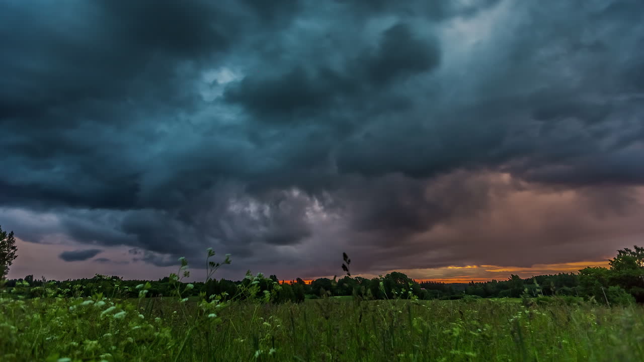 일몰 시간에 지상의 잔디에서 폭풍우 구름의 움직임의 시간 경과