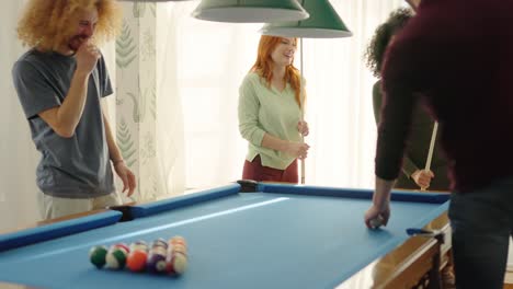 Friends laughing when woman playing awful at pool