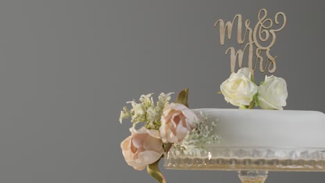 Primer-Plano-Del-Pastel-De-Bodas-En-El-Stand-Contra-El-Fondo-Gris-Del-Estudio-En-La-Recepción-De-La-Boda