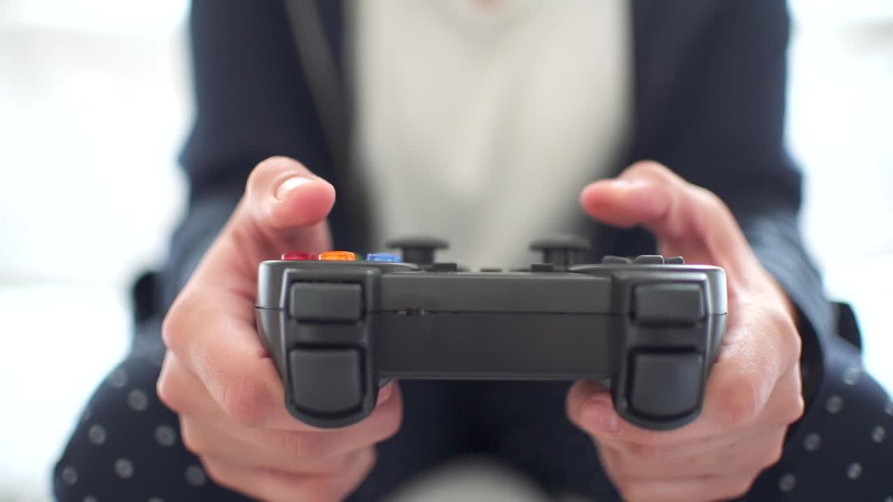 Woman's hands using gamepad close-up view playing video console game at home sitting on the sofa