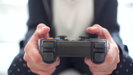 woman's hands using gamepad close-up view playing video console game at home sitting on the sofa